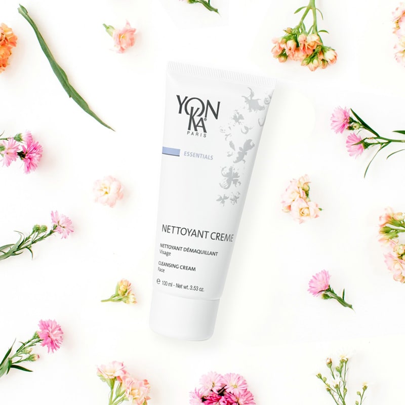 Yon-Ka Paris Nettoyant Creme (100 ml) shown top view with delicate pink and peach flowers in the background