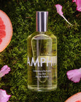 Lifestyle shot top view of Laboratory Perfumes Samphire Eau de Toilette on grass with pink flowers and grapefruit in the background