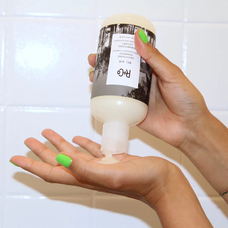 R+Co Bel Air Smoothing Shampoo - model holding bottle