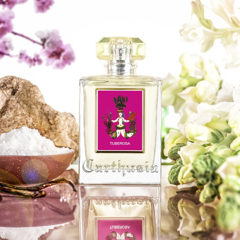 Lifestyle shot of Carthusia Tuberosa Eau de Parfum (100 ml) with ingredients and flowers in the background