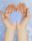 Odacite Mood Cleansing Ayurvedic Bath Soak - bath salts close-up in hands of model with water in the background