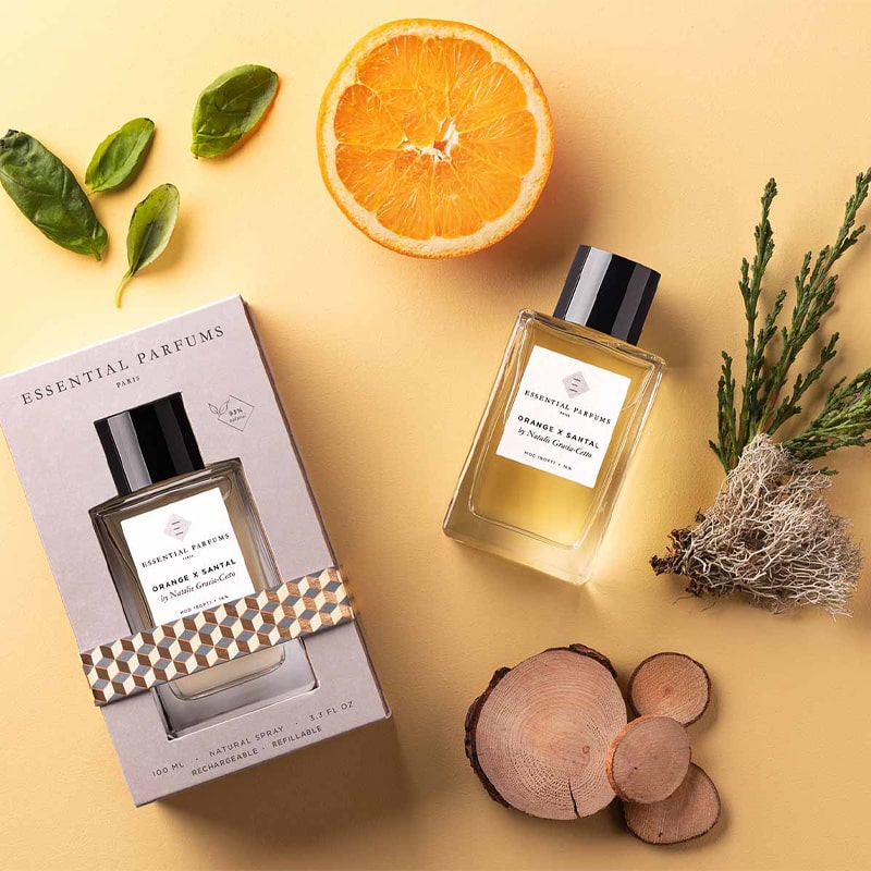 Essential Parfums Orange X Santal Perfume by Natalie Gracia Cetto with note ingredients scattered - beauty shot