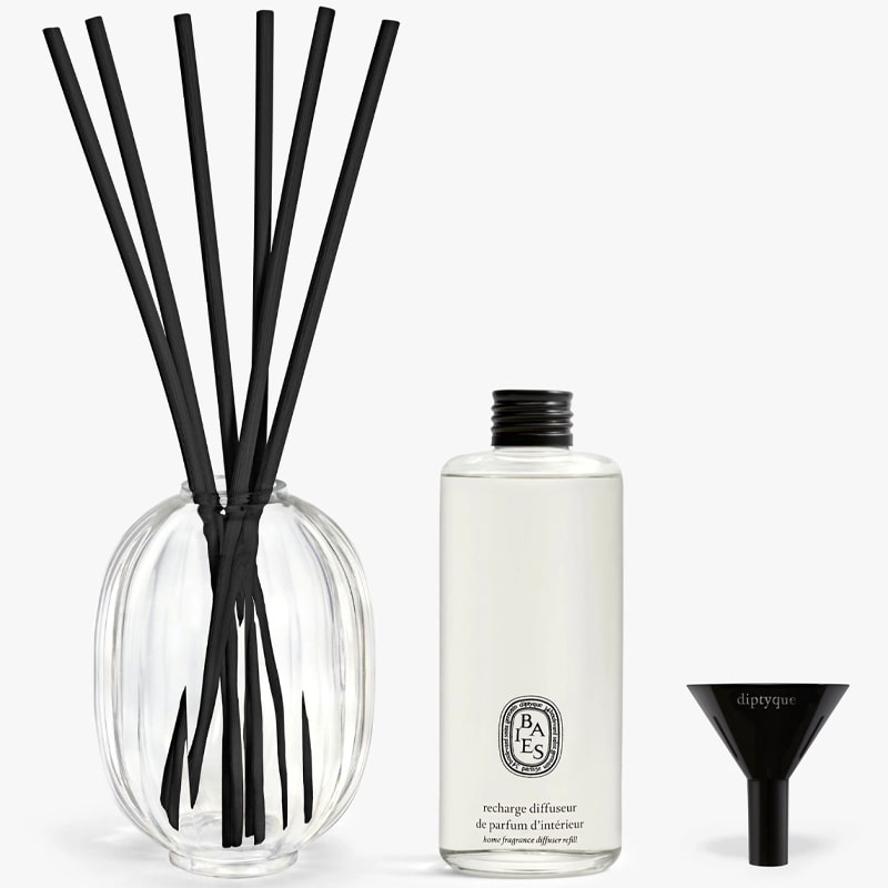 Diptyque Roses Home Fragrance Diffuser  in use, oil bottle, and funnel side by side