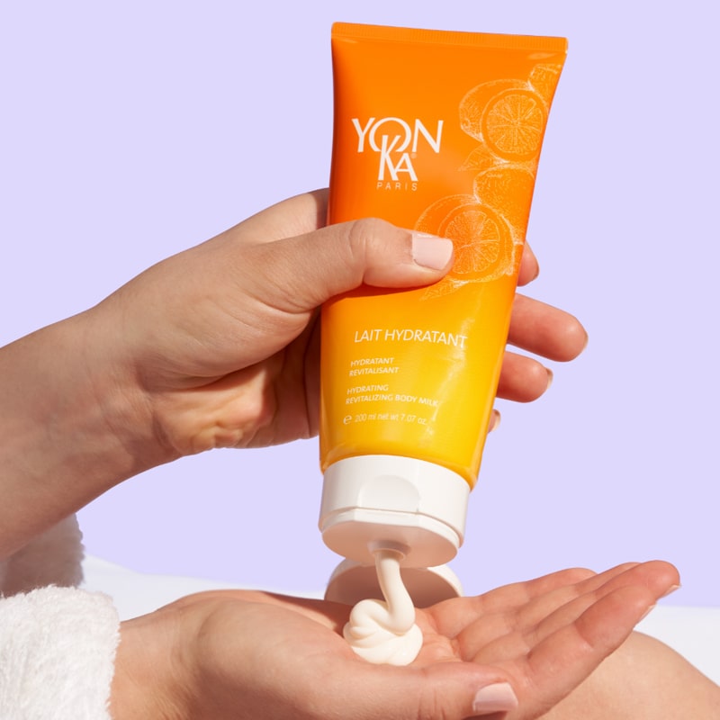model squeezing Yon-Ka Paris Lait Hydratant Vitality – Mandarin into palm of hand
