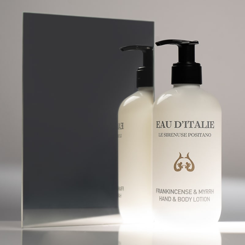 Lifestyle shot of Eau d’Italie Frankincense &amp; Myrrh Hand &amp; Body Lotion (300 ml) in front of mirror with dark gray background reflection
