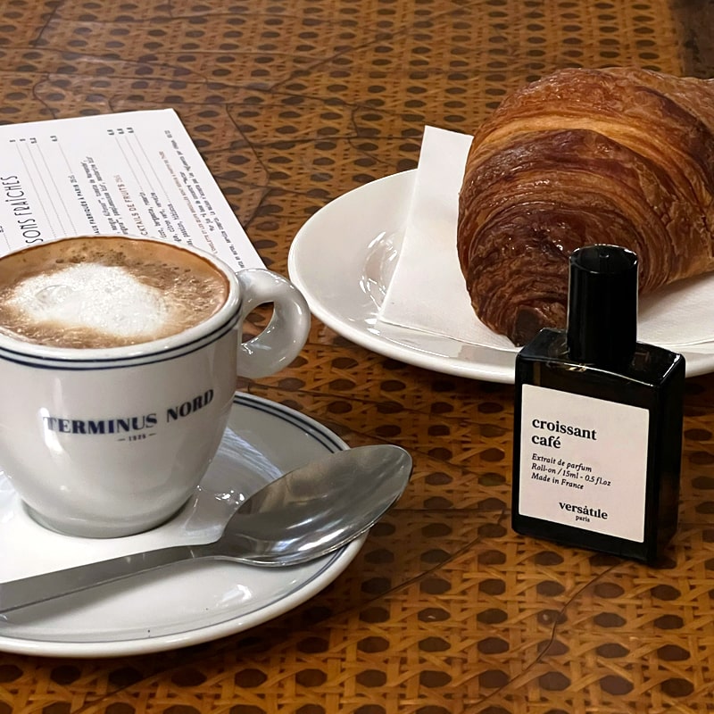 Versatile Paris Croissant Cafe Extrait de Parfum shown beside a cup of coffee and a croissant