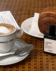 Versatile Paris Croissant Cafe Extrait de Parfum shown beside a cup of coffee and a croissant