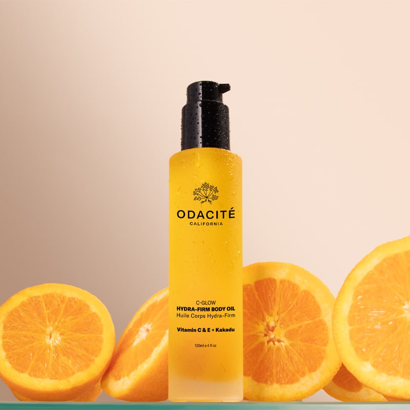 Odacite C-Glow Hydra-Firm Body Oil - Beauty shot, product shown with oranges