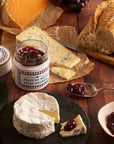 Confiture Parisienne Nuits Saint Georges Jelly - Jelly jar shown open surrounded by cheeses and bread on wood table