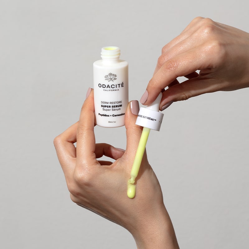Odacite Edelweiss Extreme™ Derm-Restore Super Serum - model shown holding bottle and using dropper on hands