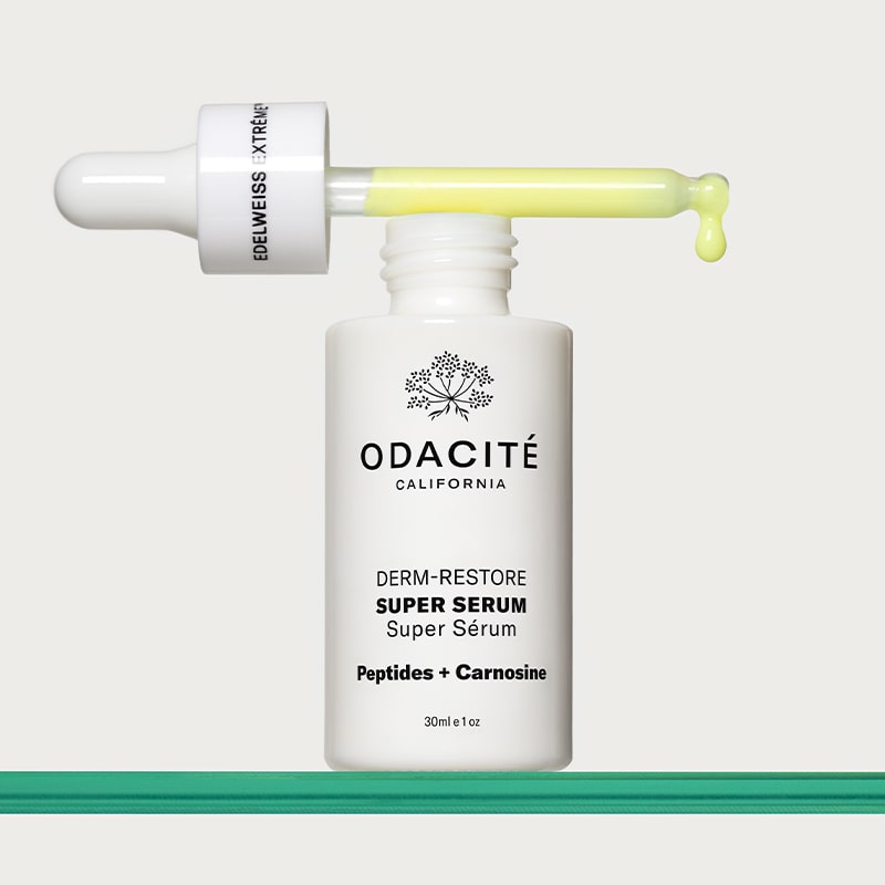 Odacite Edelweiss Extreme™ Derm-Restore Super Serum - product shown with dropper sideways on top of bottle on glass table