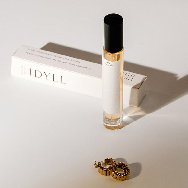 Orchid + Ash Idyll Perfume Travel Spray - Jasmine Incense + Vanilla - product shown next to packaging and earrings