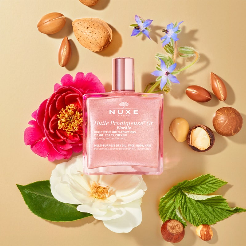 Nuxe Huile Prodigieuse Or Florale Multi-Purpose Dry Oil - product on table surrounded by ingredients 