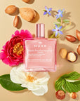 Nuxe Huile Prodigieuse Or Florale Multi-Purpose Dry Oil - product on table surrounded by ingredients 