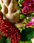 Beauty shot of ingredients including pink pepper, ginger and pink flowers in the background