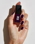 Model with light skin tone wearing and holding bottle of JINsoon Nail Lacquer - Risque