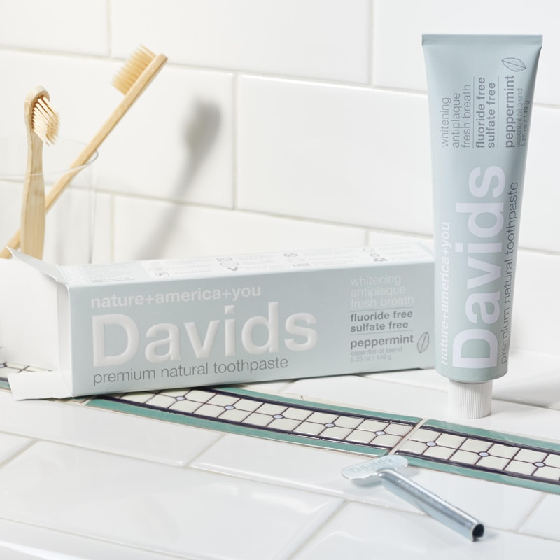 Beauty shot of Davids Premium Natural Toothpaste (5.25 oz) on sink top with brushes