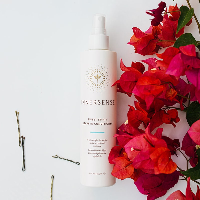 Beauty shot of Innersense Organic Beauty Sweet Spirit Leave In Conditioner 10 oz with bougainvillea and bobbie pins in the background