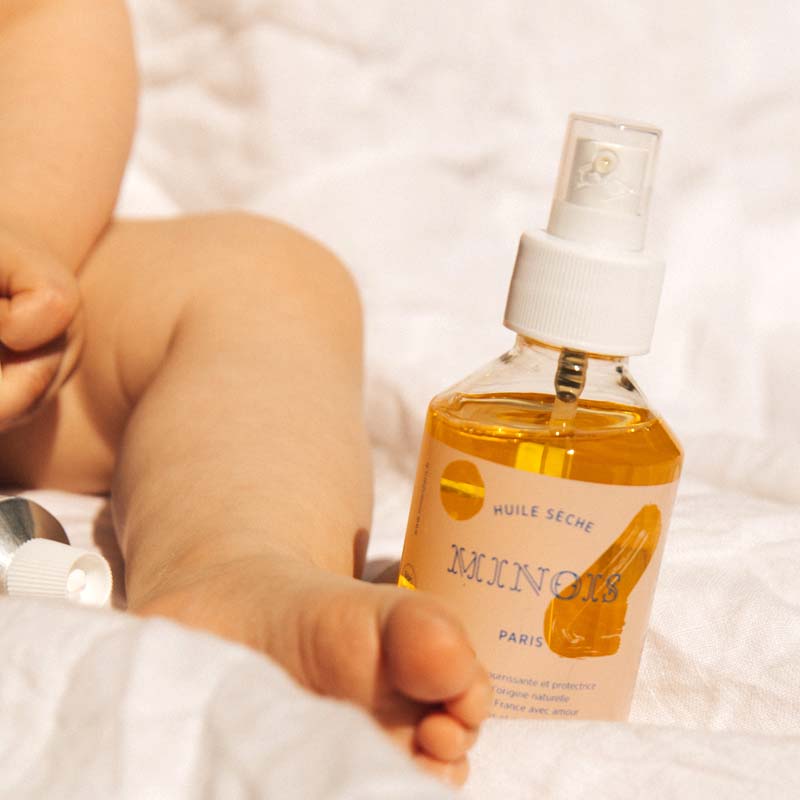 Minois Paris Huile Seche (Dry Oil) (150 ml) with leg of baby in the background