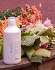 Lifestyle shot of Kerzon Lessive Parfumee (Fragranced Laundry Soap) (1 liter) with flower bouquet in the background