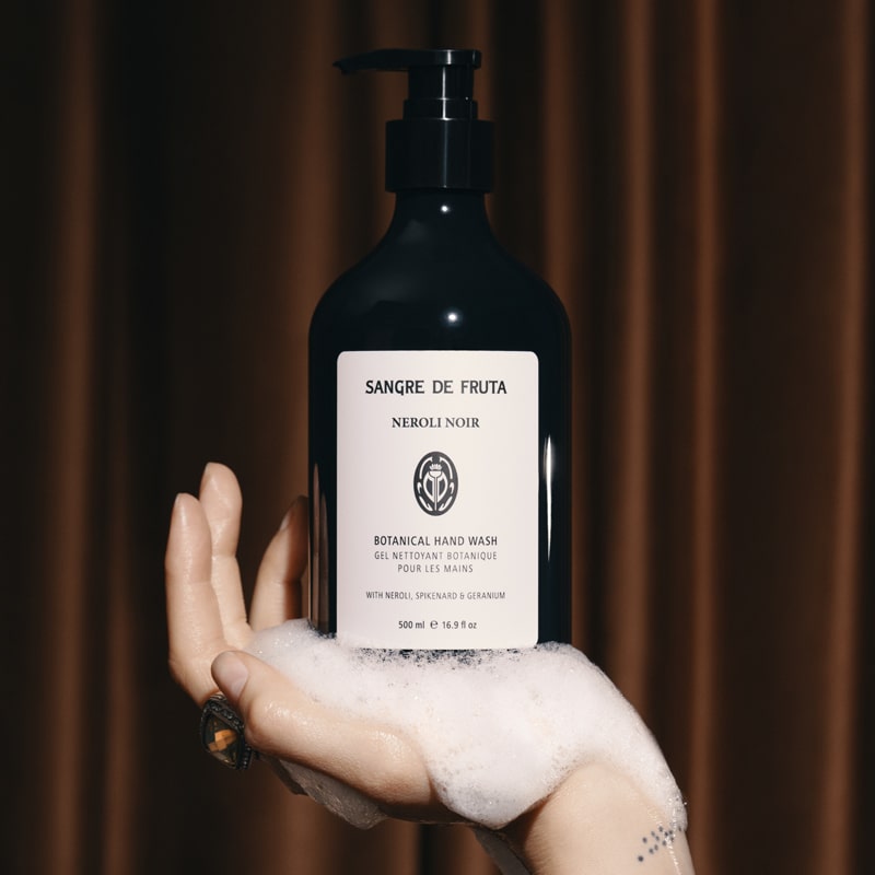 Lifestyle shot of Sangre de Fruta Botanical Hand Wash Neroli Noir (500 ml) in palm of woman&#39;s hand with soap suds