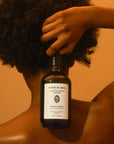 Lifestyle shot of model holding Sangre de Fruta Botanical Shampoo Garden of Earthly Delights (500 ml) bottle