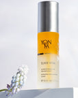 Lifestyle shot of Yon-Ka Paris Elixir Vital (30 ml) with flowers in the foreground