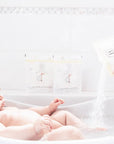 baby in bath with mother pouring in Bathorium Little Charlie Bath Soak