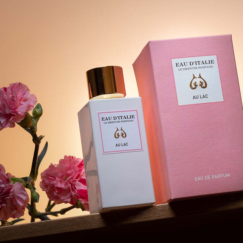 Lifestyle shot of Eau d'Italie Au Lac Eau de Parfum Spray (100 ml) with box and pink carnations in the background