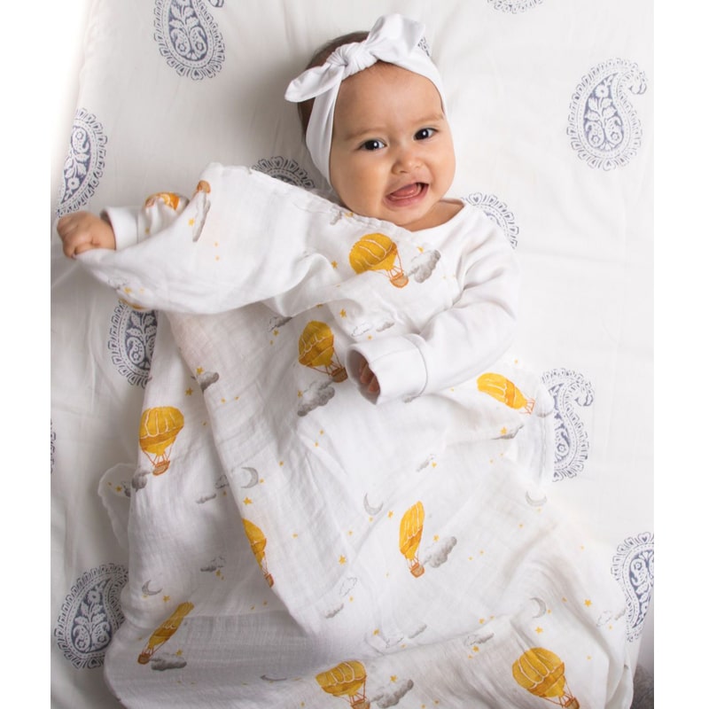 Malabar Baby Organic Cotton Muslin Swaddle – Hot Air Balloon shown partially wrapped around smiling baby (not included)