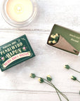 Lifestyle shot of Marvling Bros Ltd Welsh Birthday Folk Art Mini Bouquet In A Matchbox with flowers out of bouquet and next to a candle