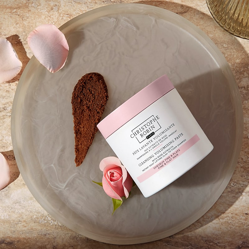 Christophe Robin Cleansing Volumizing Paste with Pure Rassoul Clay and Rose Extracts beauty shot of jar on tray with product smear and a rosebud