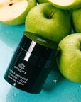 Odacite Green Smoothie Quenching Creme leaning against green apples