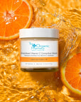 The Organic Pharmacy Stabilized Vitamin C Corrective Mask beauty shot in water beside orange slices