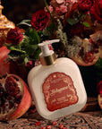 Santa Maria Novella Melograno Fluid Body Cream surrounded by red roses, pomegranates 