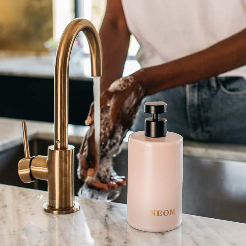 NEOM Organics Real Luxury Ceramic Hand Wash Dispenser &amp; Refill showing model using hand wash 
