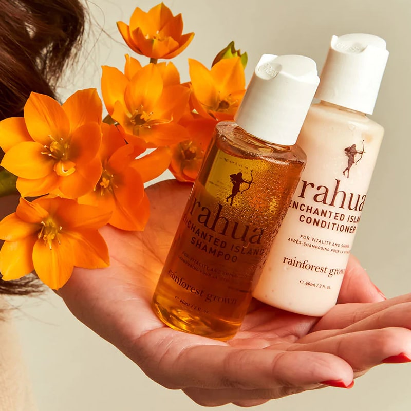 Rahua by Amazon Beauty Enchanted Island Travel Duo showing in models hand with orange flowers