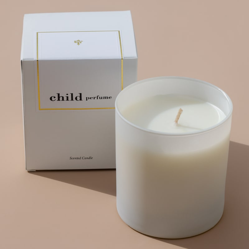 Lifestyle shot of Child Perfume Scented Candle 8 oz shown with box and tan background