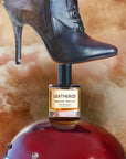 D.S. & Durga Leatherize Eau de Parfum - beauty shot of bottle under a black boot and on top of a helmet