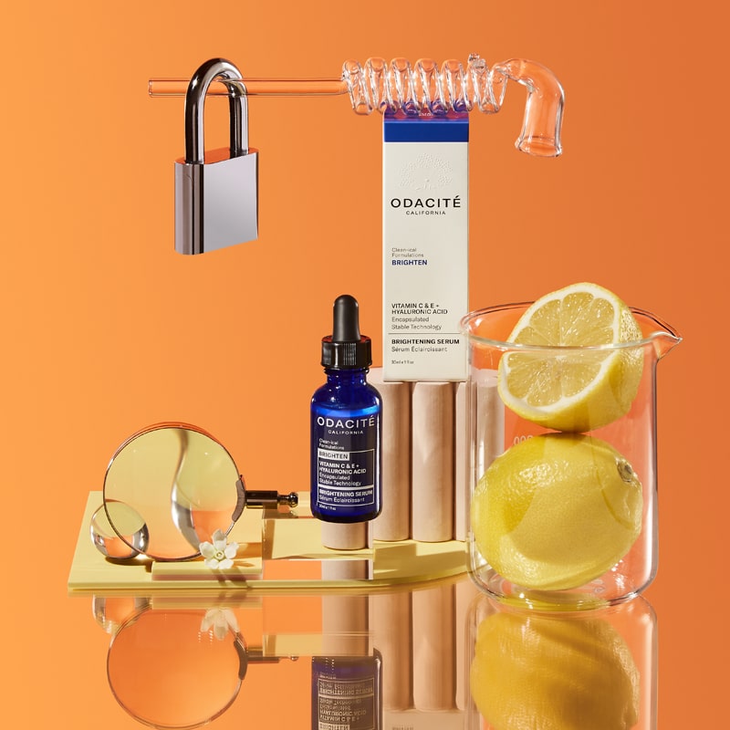 Odacite Vitamin C & E + Hyaluronic Acid Brightening Serum beauty shot with orange background and lemons