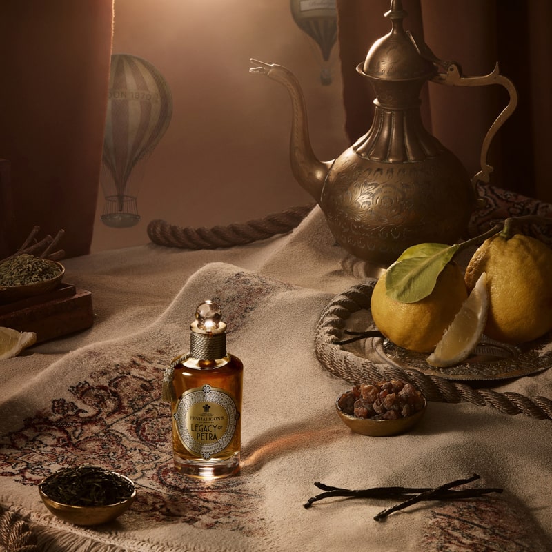 Penhaligon&#39;s Legacy of Petra Eau De Parfum - Beauty shot product shown on blanket next to lemons and herbs and spices. 