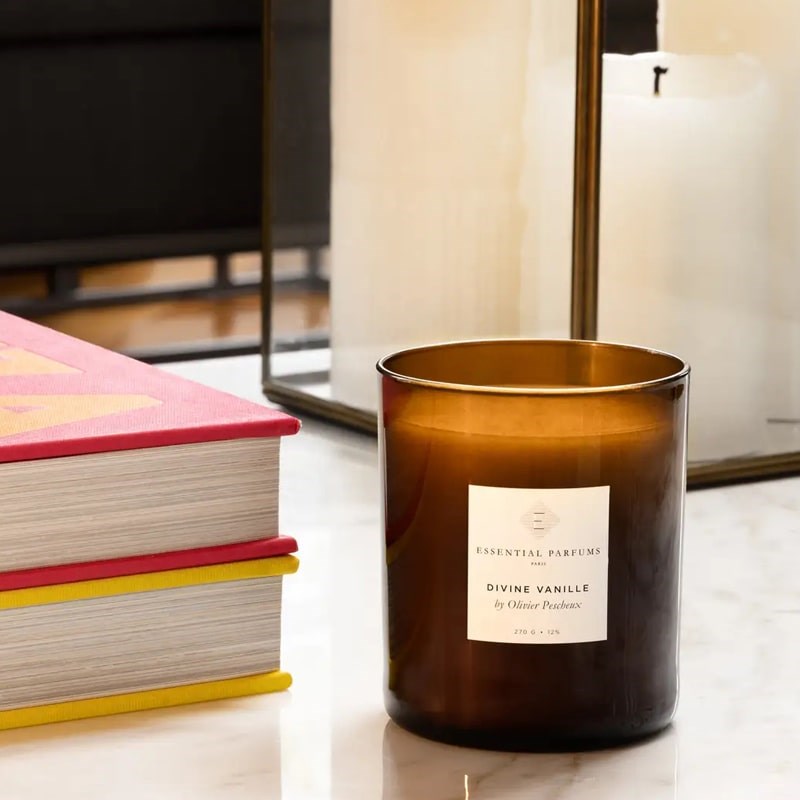 Essential Parfums Divine Vanille Scented Candle - Product displayed on table next to books