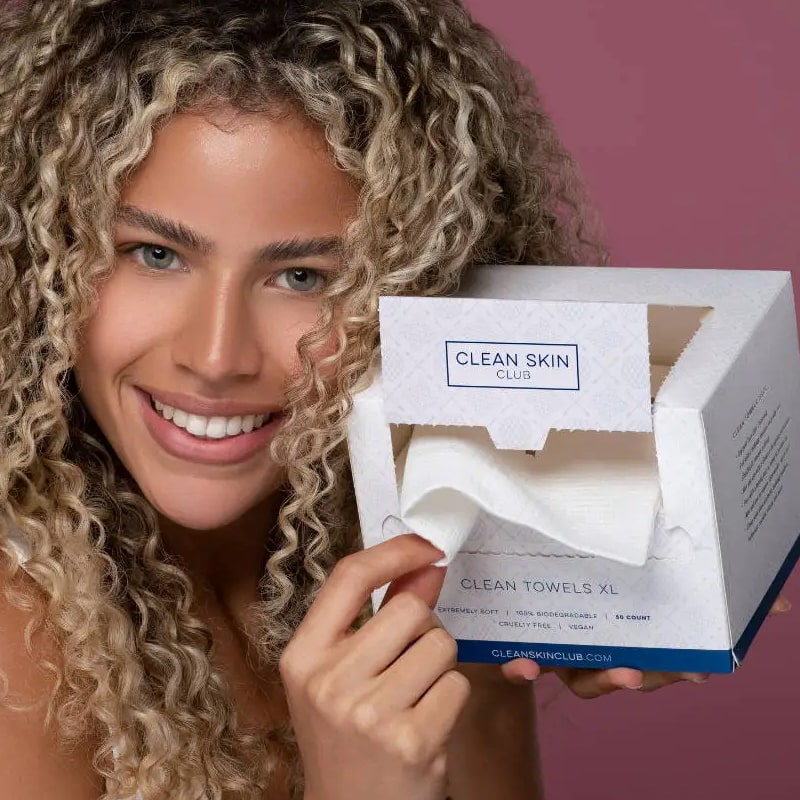 Model with opened box of Clean Skin Club Clean Towels XL pulling sheet out