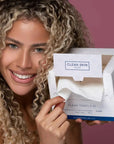 Model with opened box of Clean Skin Club Clean Towels XL pulling sheet out
