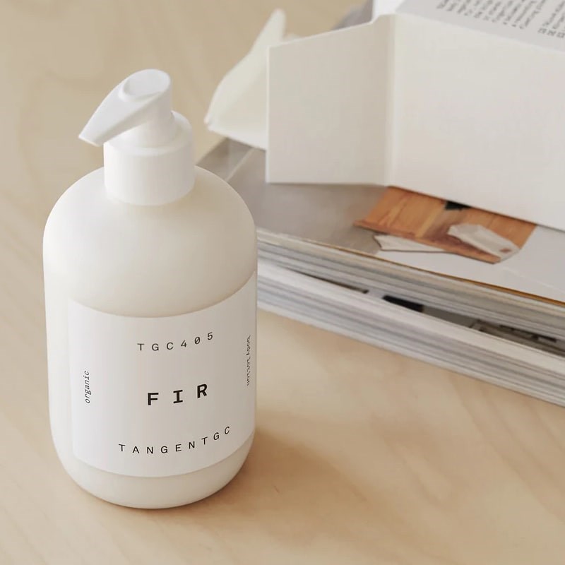 Tangent GC Fir Body Lotion - Product displayed on table next to magazine