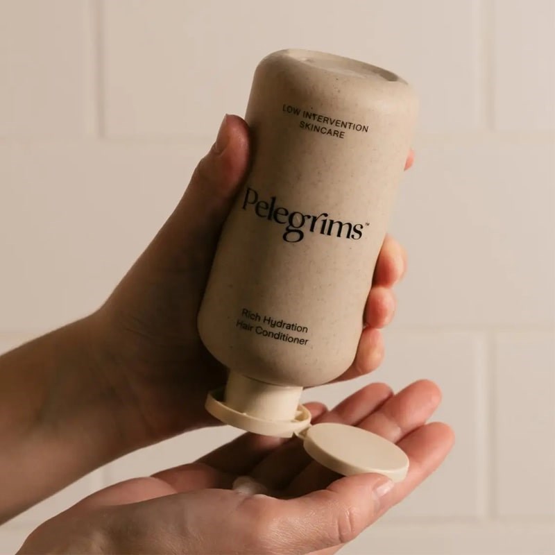 Pelegrims Rich Hydration Hair Conditioner - Model shown dispensing product into hand