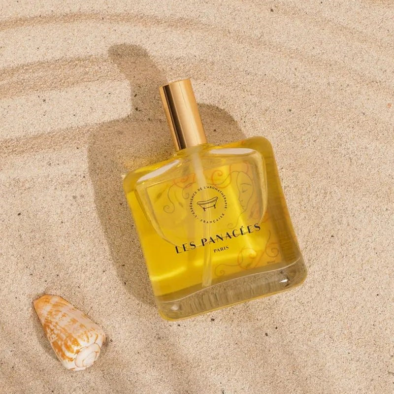 LES PANACEES Nourishing Dry Body and Hair Oil - Summer Tourbillon - Product displayed on beach sand