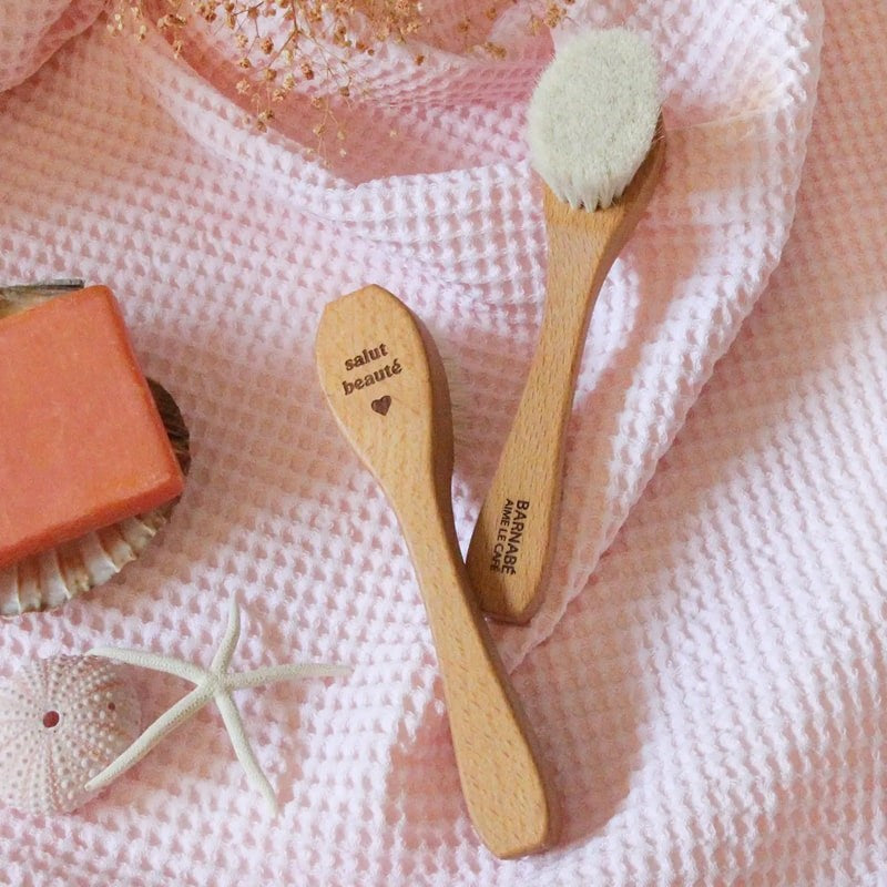Barnabe Aime Le Cafe Wooden Facial Cleansing Brush - Product displayed on pink quilted background