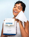 Clean Skin Club Clean Towels XL Supreme - model holding towel to face and holding towel packaging