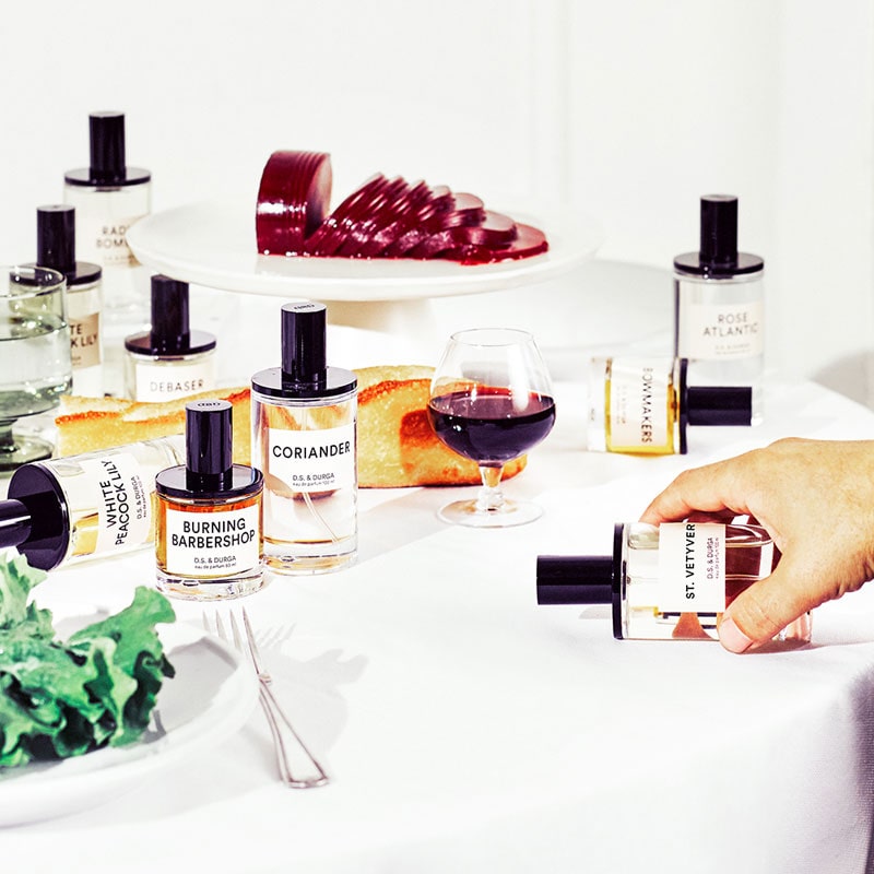 D.S. &amp; Durga fragrances on a table with a glass of wine and cranberry sauce - beauty shot